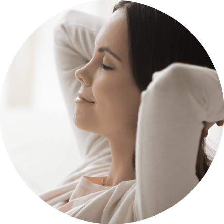 lecsukott szemű derűs nő, tarkóra tett kézzel